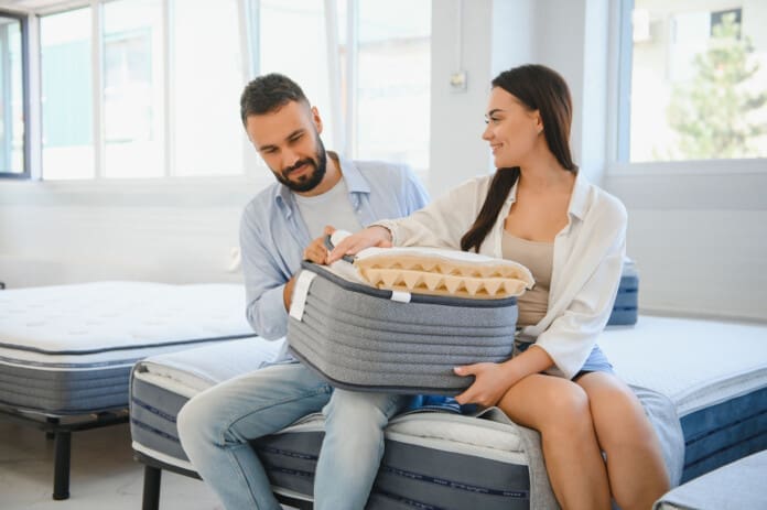 A beautiful young couple chooses a new mattress in a store