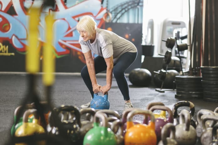 Senior woman in gym lifting kettlebell