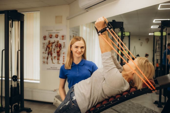 A physiotherapist helps an elderly woman in a rehabilitation center