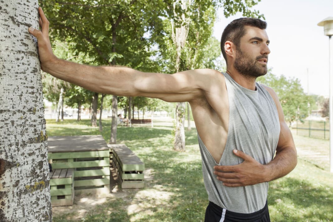 Sportsman stretching body in park