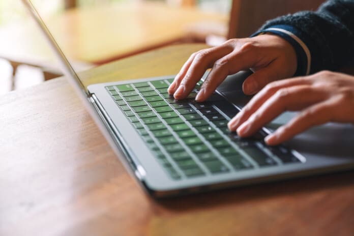 Closeup image of hands using and typing on laptop computer keybo