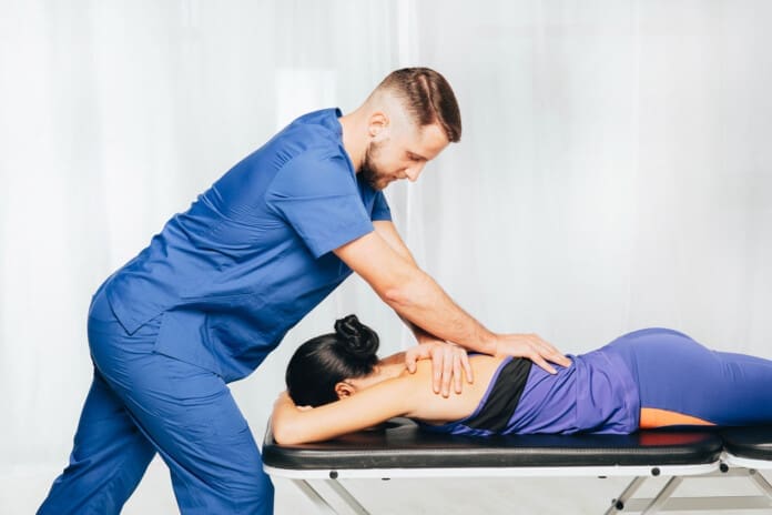 Physiotherapist giving back massage to female patient