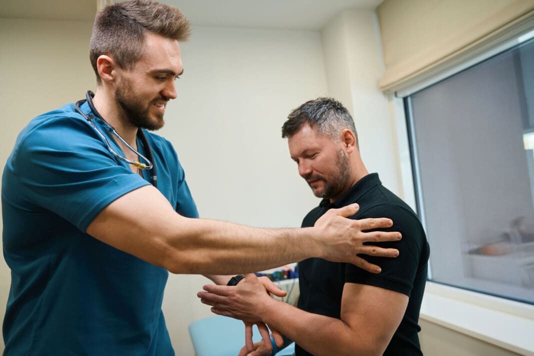 Experienced physiotherapist testing upper extremity strength in patient