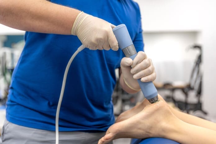 Physiotherapist performs ultrasound therapy on female patient knee. Joint rehabilitation. Shockwave Therapy and Chiropractic: Evidence and Insights