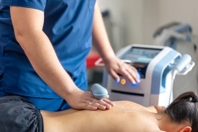 Doctor using machine to treat the back of a patient.