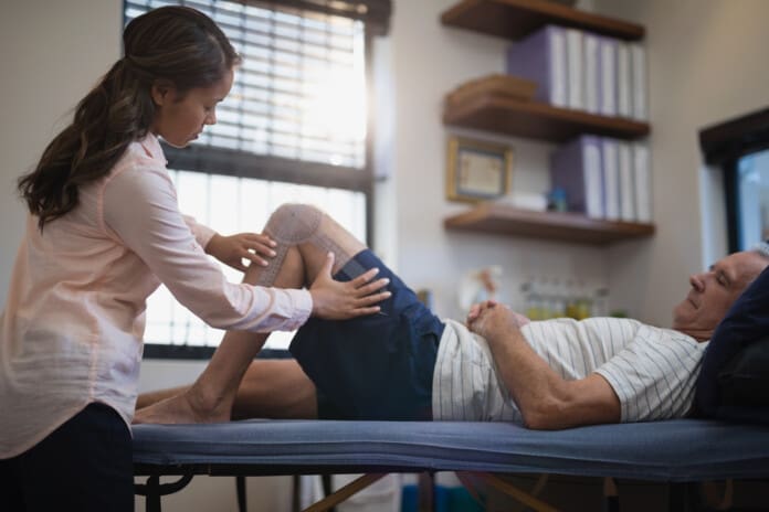 female-therapist-measuring-knee-while-senior-male-2026-03-26-11-50-30-utc