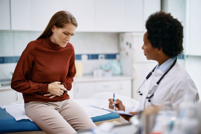 Mid adult woman with stomachache having medical appointment at doctor's office.