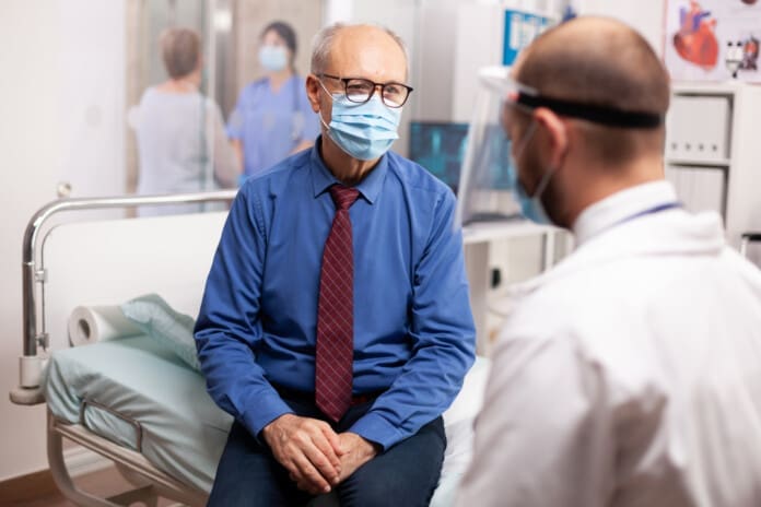 Doctor in the course of covid outbreak consulting senior man