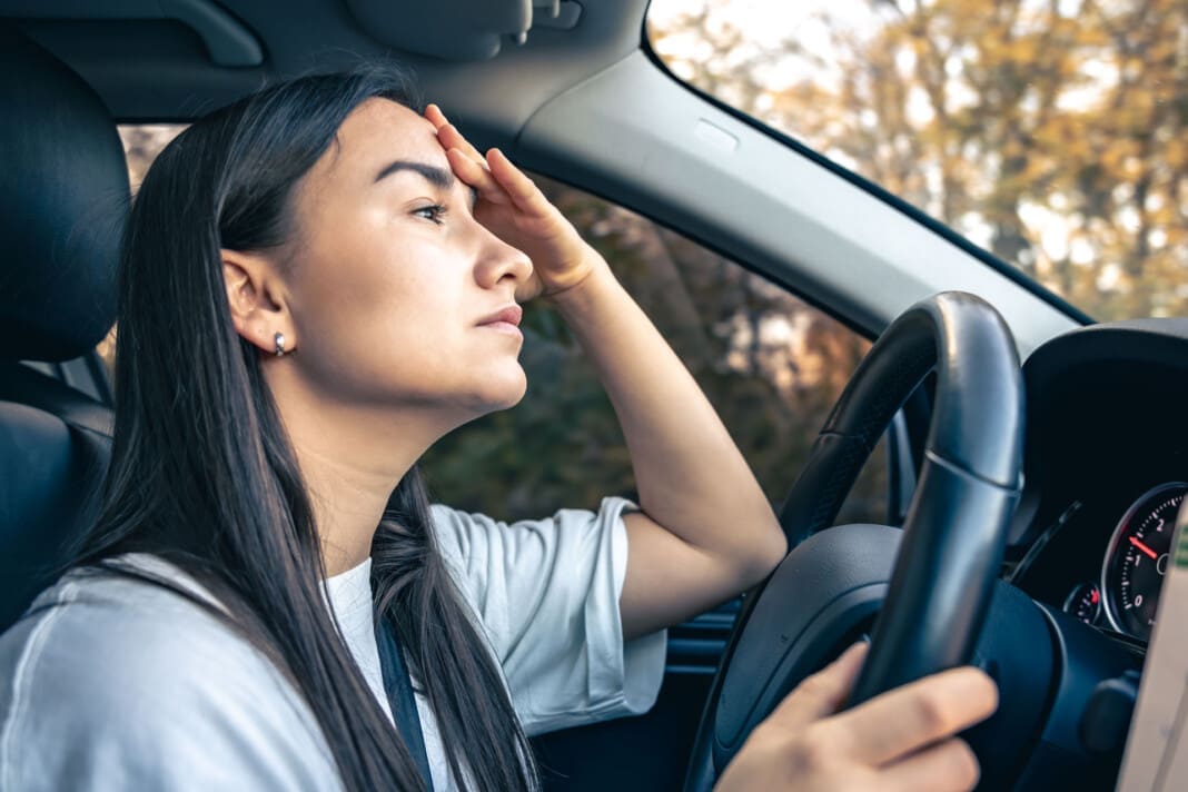 Tired young woman car driver suffering from headache migraine driving vehicle. Heat-Related Car Accidents in El Paso: Essential Precautions